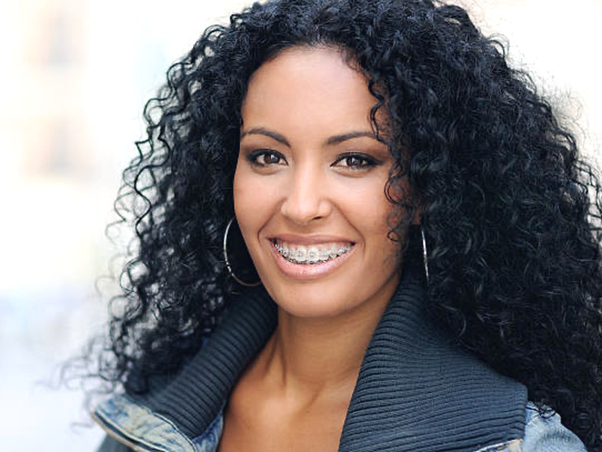 Smiling adult woman wearing braces during orthodontic treatment