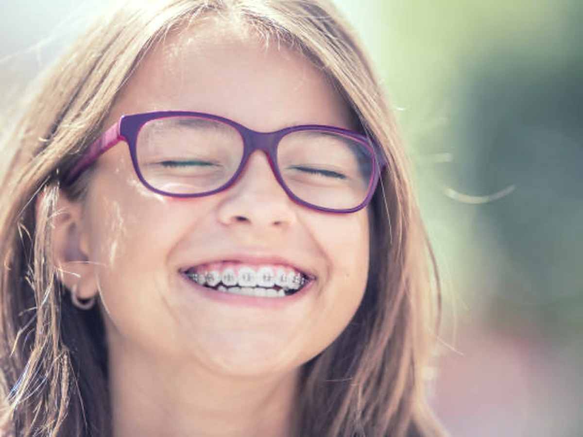 Smiling girl wearing braces after early orthodontic treatment